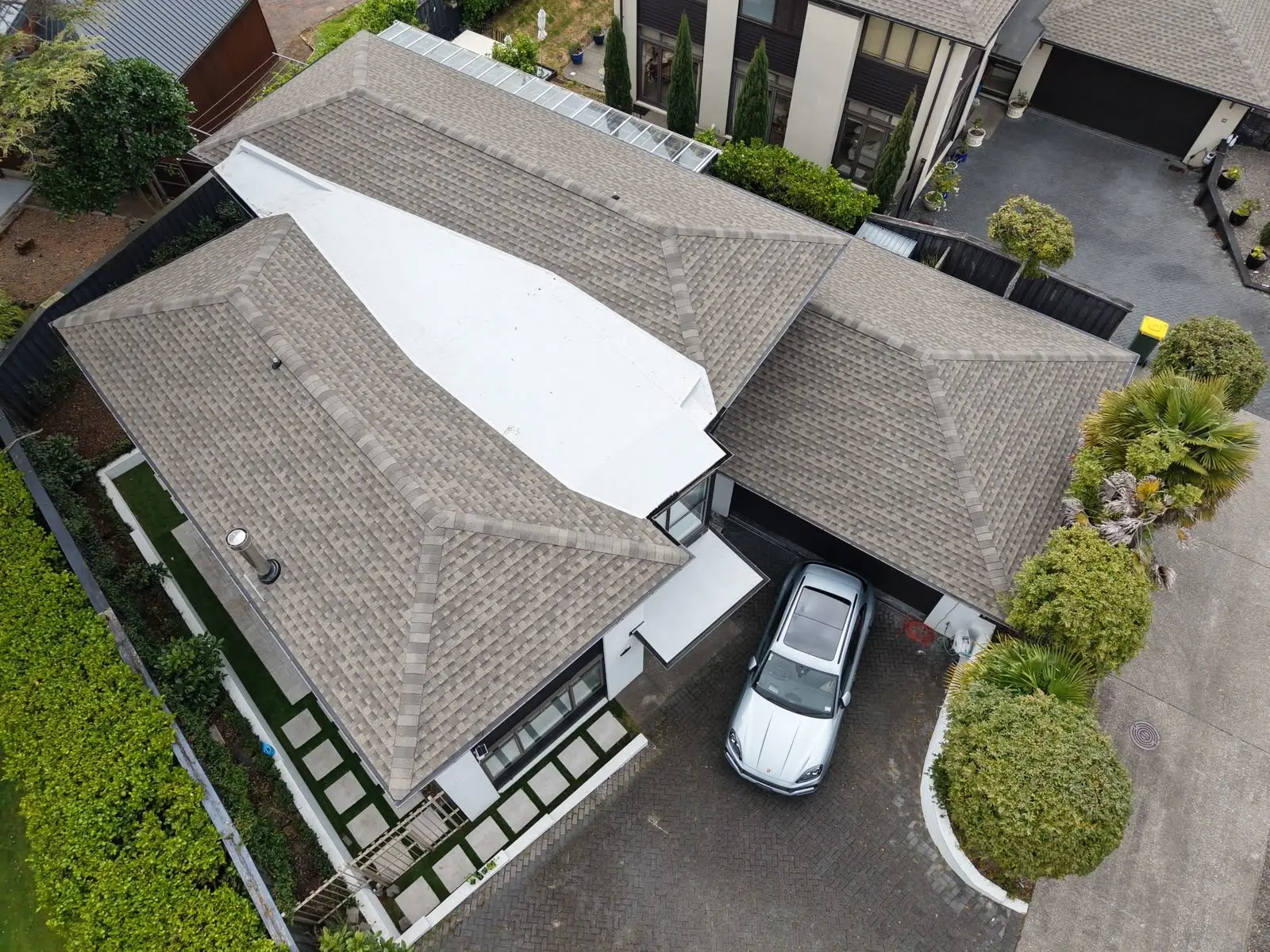 Aerial view of a shingle roof with a white membrane flat roof section