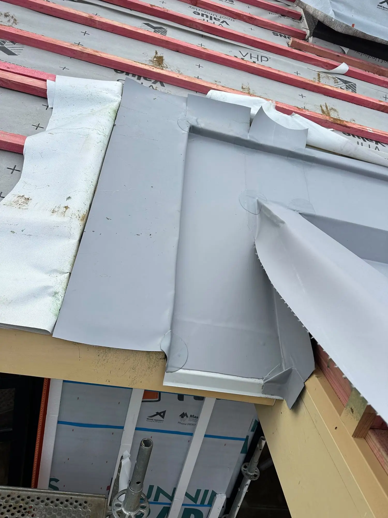 Membrane saddle flashing formed behind a roof penetration in Auckland